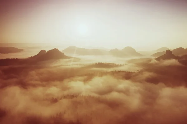 Marvolous red daybreak. Misty daybreak in a beautiful hills. Peaks of hills are sticking out from foggy background, the fog is red and orange due to Sun rays. — Stock Photo, Image