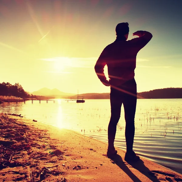 Silhouette of slim person ondecline seeing off sun. Mn with hand in the air — Stock Photo, Image
