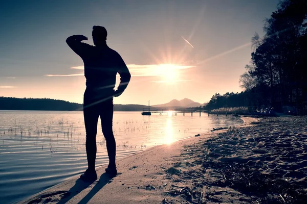 Silhouette of slim person ondecline seeing off sun. Mn with hand in the air — Stock Photo, Image