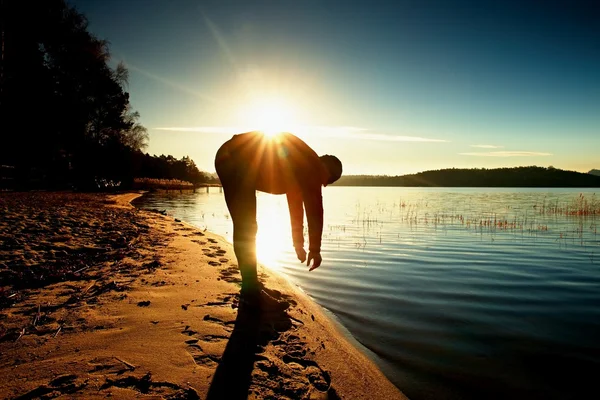 Silueta de deporte activo hombre adulto corriendo y haciendo ejercicio en la playa. Agua tranquila, isla y cielo soleado fondo . — Foto de Stock