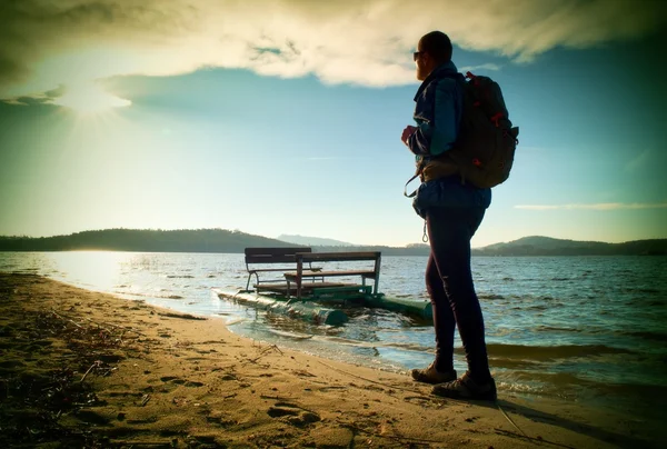海に沿って歩きます。さびたペダルのボートでビーチでバックパック歩く男。秋の海. — ストック写真