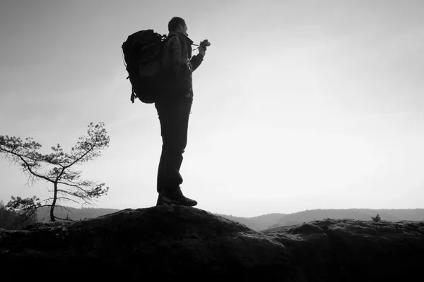 Amatérský fotograf má fotografie s zrcadlový fotoaparát na vrcholu skály. Zasněný Pogy krajina, jaro oranžové růžové mlhavé svítání — Stock fotografie