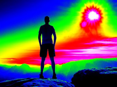 Adam kayalık tepe üzerinde. Fantastik Kızılötesi tarama. Ağır Sis içinde ultra violet ölçü renklerde derin vadi