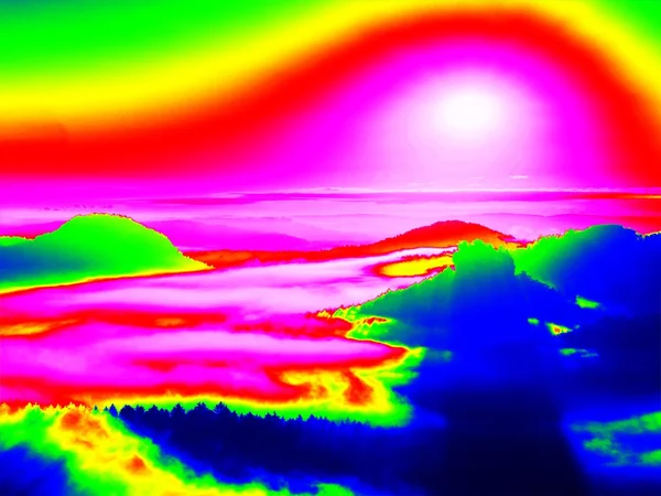 Инфракрасное сканирование скалистого ландшафта, соснового леса с красочным туманом, над ним жаркое солнечное небо. Удивительные цвета термографии . — стоковое фото