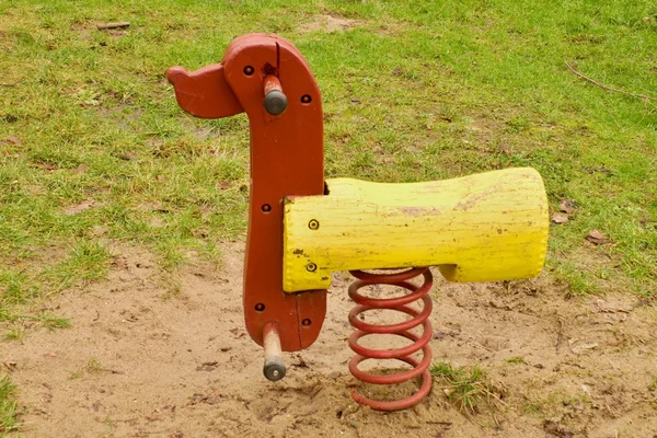 Children colorful wooden swinging dog in playground. Wooden seesaw. — Stock Photo, Image