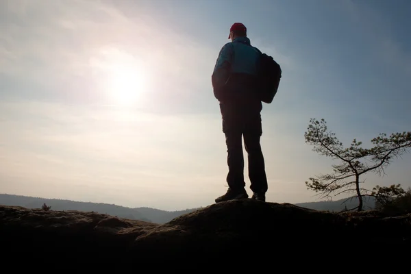 Un hombre con una gran mochila en la roca. Soleado amanecer de primavera — Foto de Stock