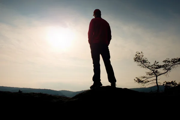 Homem com boné vermelho no pico rochoso. Homem a caminhar sobre o cume rochoso até Sun. Belo momento o milagre da natureza . — Fotografia de Stock