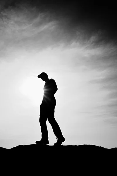 Hombre con gorra roja en pico rocoso. Hombre caminando sobre la cumbre rocosa hacia el Sol. Hermoso momento el milagro de la naturaleza . — Foto de Stock