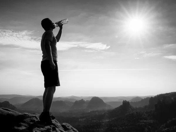 口渴的徒步旅行者黑裤子从瓶水饮料。在砂岩岩石公园萨克森瑞士的山峰上汗累的旅游 — 图库照片