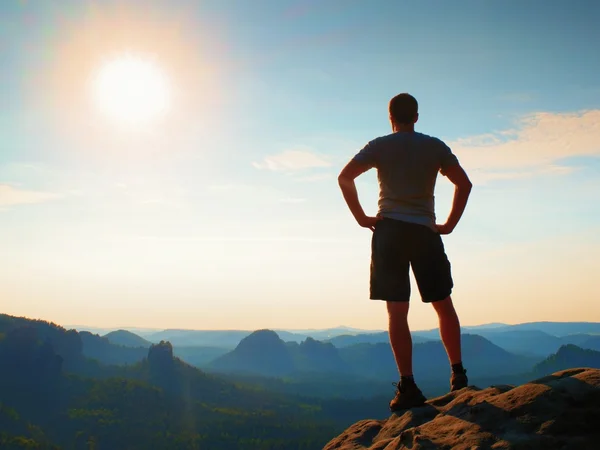 Happy hiker berdiri di tebing yang tajam di taman batu kerajaan dan mengawasi berkabut dan berkabut pagi lembah ke Sun . — Stok Foto