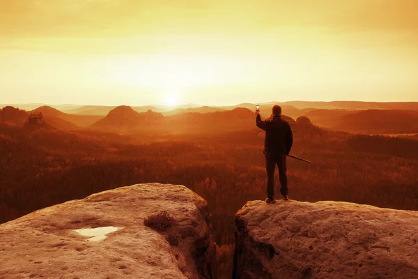 高旅游指导石上，杆在手。与运动背包徒步旅行者站在悬崖边上迷雾笼罩的山谷。阳光明媚的春天黎明在洛矶山脉. — 图库照片
