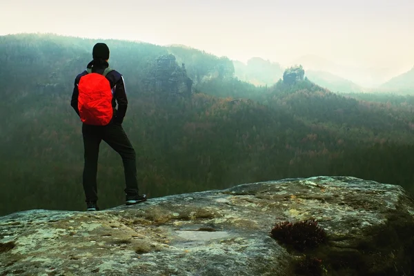 Caminhante com mochila vermelha na rocha de arenito afiada no parque de impérios de rocha e observando o nebuloso e nebuloso vale da primavera — Fotografia de Stock