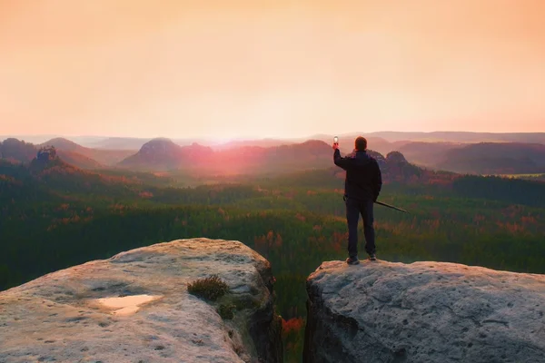 Wandelaar staan met slimme telefoon bovenop de berg en genieten van voorjaar zonsopgang. Toeristische gids — Stockfoto