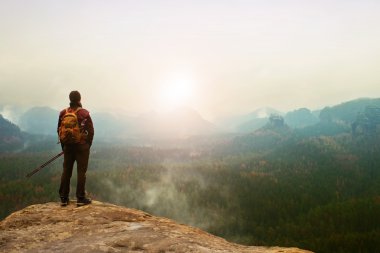Sırt çantası ve Polonyalılar cliff ve derin puslu Vadisi feryat izlerken ile turist. Güneşli bahar günü dağlarda.