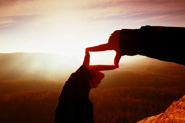 Close up hands making frame gesture. Orange misty valley bellow. Sunny spring daybreak in mountains. — Stock Photo, Image