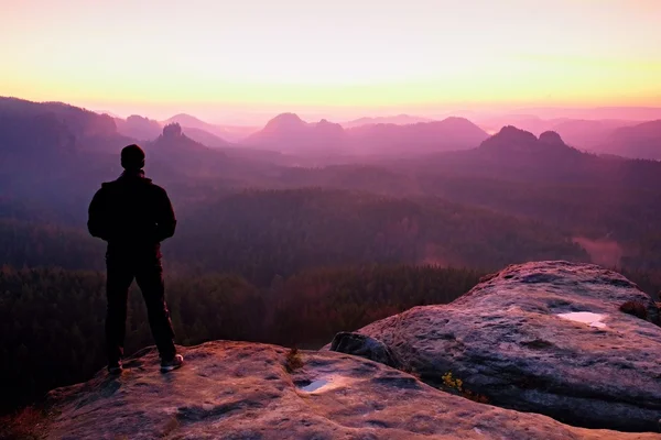 Tall man in het zwart op de klif en kijken naar de berg zonsopgang. Silhouet in zelfbewuste houding — Stockfoto