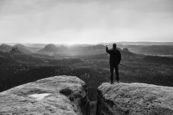 Hiker stand with smart phone on top of mountain and enjoying spring sunrise. Tourist guide