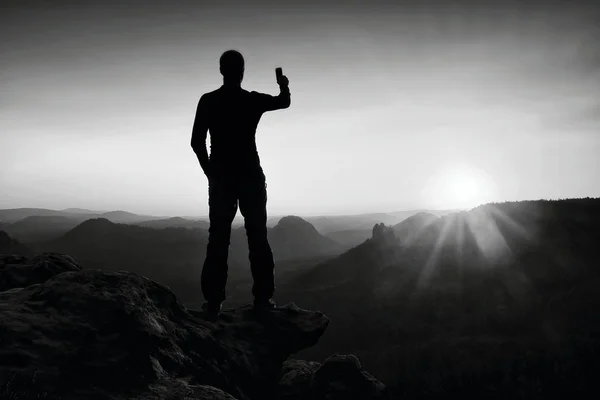 Selfie μανία. Ψηλός άνδρας πεζοπόρος παίρνει selfie φωτογραφία από το έξυπνο τηλέφωνο στην κορυφή του βουνού με την Ανατολή. — Φωτογραφία Αρχείου