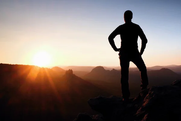 Un hombre tiene las manos en las caderas. Silueta deportiva en la naturaleza al amanecer . — Foto de Stock