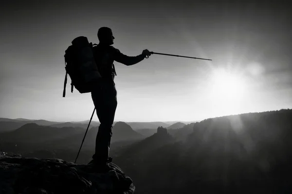 Silhouette nette d'un grand homme au sommet de la montagne avec soleil dans le cadre. Guide touristique en montagne — Photo