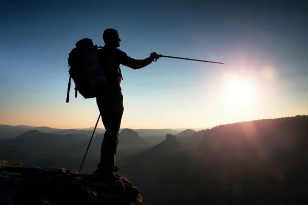 Sharp silhouette of a tall man on the top of the mountain with sun in the frame. Tourist guide in mountains — Stock Photo, Image