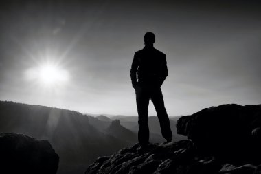 Keskin kayalık dağ zirvesine üzerinde ince turist Sun Vadisi'ne puslu ve sisli sabah üzerinde izliyor