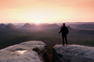 Uzun yürüyüşe çıkan kimse sportif sırt çantası ile kayalık Görünüm noktası puslu Vadisi üzerinde durmak. Güneşli Bahar şafak