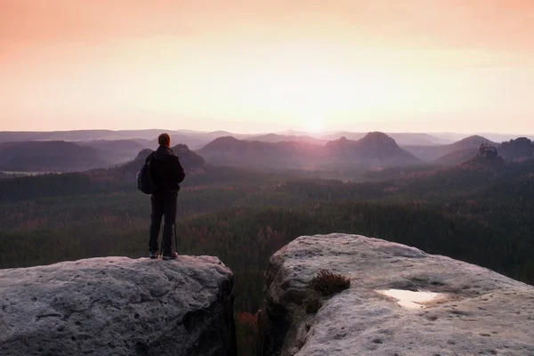 Hiker with sporty backpack stand on rocky view point above misty valley.  Sunny spring daybreak — Stock Photo, Image