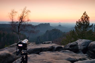 Güneş battıktan sonra dağ tepe üzerinde büyük fotoğraf makinesi standlı tripod. Keskin kumtaşı kayalıklarla