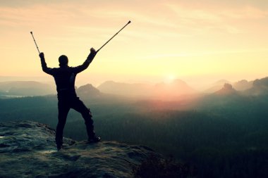 Uzun yürüyüşe çıkan kimse başının üstünde ilaç koltuk değneği ile dağ tepe elde. 