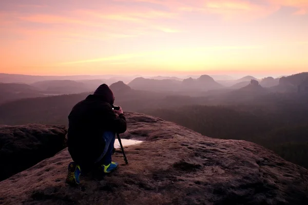 Fotógrafo profissional com tripé em penhasco e trabalho. Paisagem nebulosa sonhadora — Fotografia de Stock