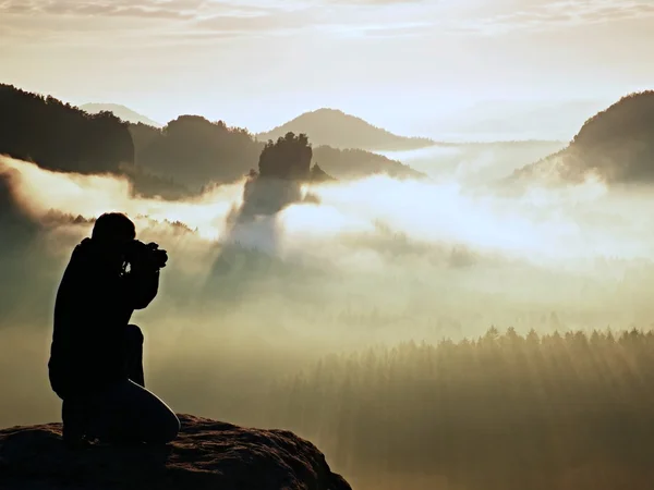 Silueta de fotógrafo profesional sobre un mar de nubes, montañas brumosas —  Fotos de Stock