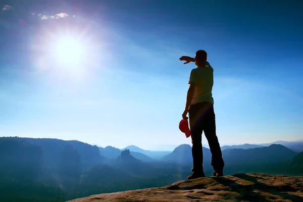 Turysta w Czerwonym Kapturku na szczyt skały w skale imperiów parku i oglądanie nad doliną mgliste i mgliste rano Sun. piękny podróż. — Zdjęcie stockowe