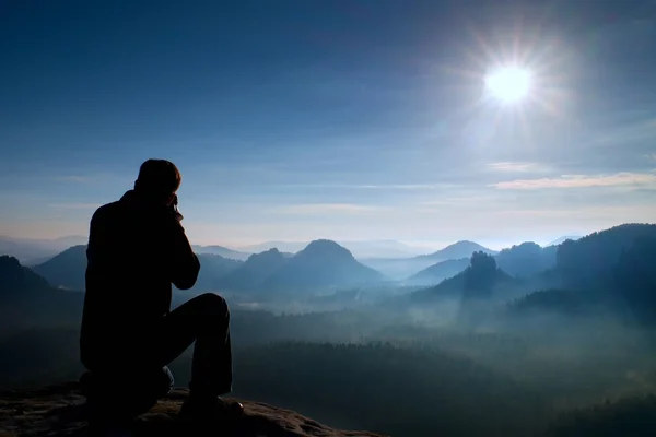 Professionele fotograaf neemt foto's met spiegel camera op Top van de rots. Dromerige landschap, oranje zon op horizon — Stockfoto