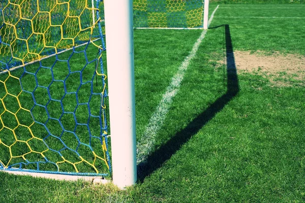 Pendurar redes de futebol dobrado, futebol líquido. Grama no campo de jogos de futebol no fundo — Fotografia de Stock