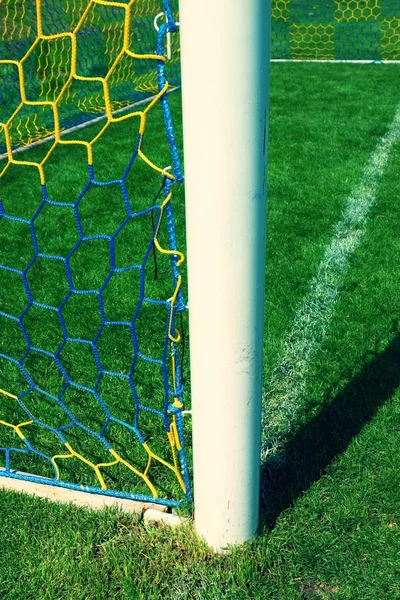 Colgar redes de fútbol dobladas, red de fútbol. Hierba en el patio de fútbol en el fondo —  Fotos de Stock
