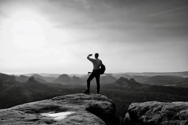 Rocky mountains. Tramp s velkým batohem stojí na skalní vyhlídka nad mlhavé údolí. — Stock fotografie