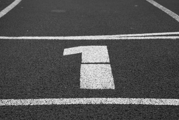 Number one. White track number on red rubber racetrack, texture of running racetracks in stadium