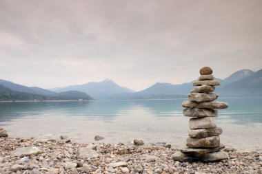 Mavi su dağ Gölü'nün kıyısında taş pyramide dengeli.