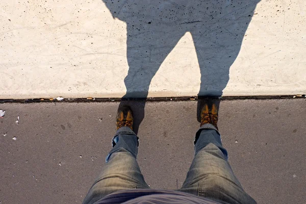 Hombre piernas largas de pie en la calle en la pared de hormigón con sombra — Foto de Stock