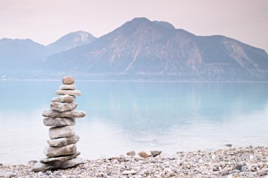 Dağ göl kıyısındaki dengeli taşı. Çakıl taşları piramit inşa çocuk 