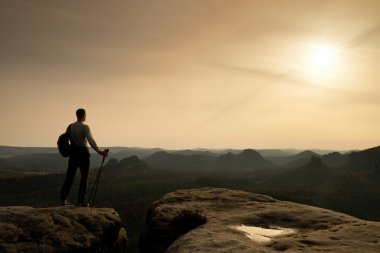 Turist cliff üzerinde el ile kutup kenar ve sırt çantası 