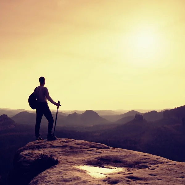 Tourist on cliff edge with pole in hand and backpack — Stock Photo, Image