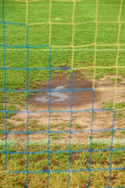 Vista desde la puerta de fútbol al agua y muda en el pobre campo de fútbol. Césped dañado en el estadio de fútbol al aire libre —  Fotos de Stock