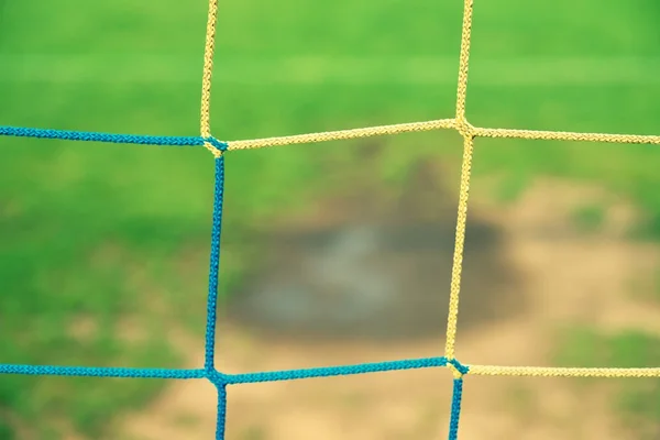 Vista do portão de futebol para a água e mude no campo de futebol pobre. Gramado danificado no estádio de futebol ao ar livre — Fotografia de Stock