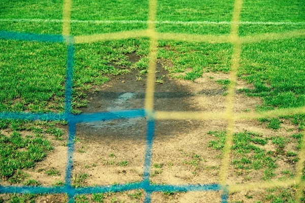 Vista desde la puerta de fútbol al agua y muda en el pobre campo de fútbol. Césped dañado en el estadio de fútbol al aire libre — Foto de Stock