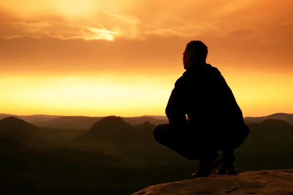 Короткие волосы турист в рубашке сидеть на скале, наслаждаться туманным пейзажем — стоковое фото