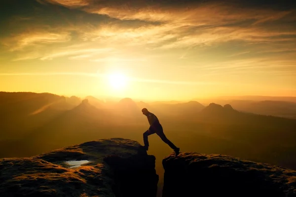 Glücklicher Mann springt zwischen Felsen, nebligen Bergen. — Stockfoto