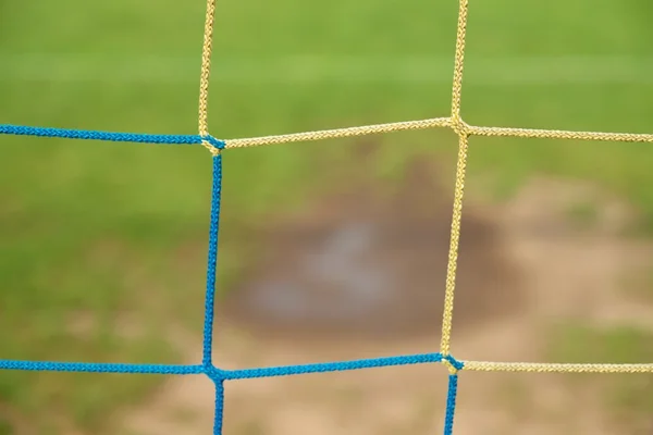 Blick vom Fußballtor auf Wasser und Schlamm im armen Fußballplatz. Beschädigter Rasen im Fußballstadion — Stockfoto