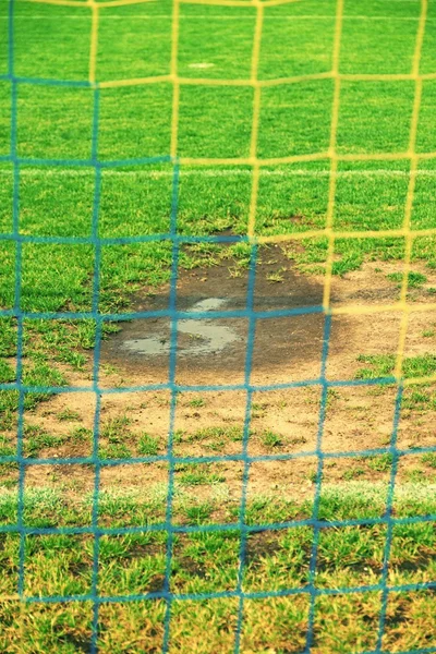 Vista do portão de futebol para a água e mude no campo de futebol pobre. Gramado danificado no estádio de futebol ao ar livre — Fotografia de Stock